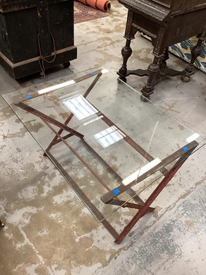 Lot 1525 - Contrived coffee table made up of an inverted, rusty and painted red, saw horse in cast iron plus a reinforced glass top.