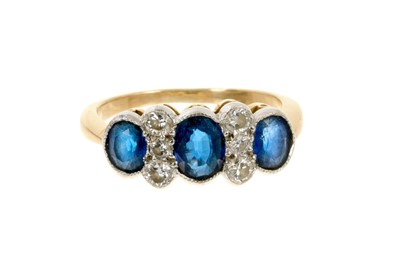 Lot 615 - Sapphire and diamond ring with three oval mixed cut blue sapphires and six brilliant cut diamonds in millegrain setting on 18ct gold shank