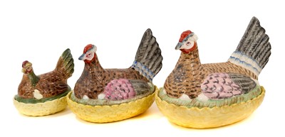Lot 77 - Good set of three 19th century graduated pottery hens on nests, with yellow basket bases, the largest 27.5cm across