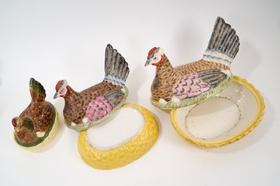 Lot 77 - Good set of three 19th century graduated pottery hens on nests, with yellow basket bases, the largest 27.5cm across