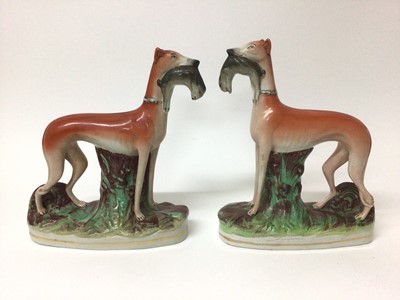 Lot 81 - Pair of Victorian Staffordshire figures of greyhounds, shown standing on naturalistic bases with rabbits in their mouths, 28.5cm and 30cm high