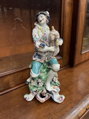 Lot 492 - Bow figure of a piper, c.1765, shown seated on a tree stump with applied flowers and leaves, on a scrollwork base, 21.5cm height