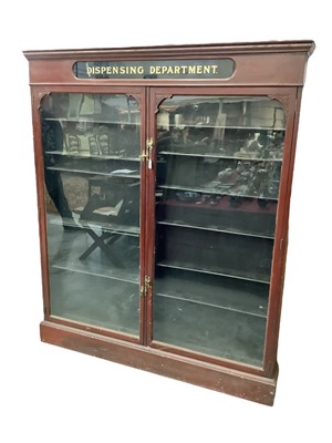 Lot 1343 - Victorian mahogany chemist's cabinet, the frieze with inset gilt emblazoned sign 'DISPENCING DEPARTMENT', with shelved interior enclosed by pair of glazed doors, on plinth base, 153cm wide x 18cm d...