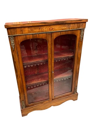 Lot 1302 - Victorian walnut and gilt metal mounted pier cabinet, inlaid to the frieze and with leather fringed shelves enclosed by a pair of glazed doors, 79cm wide x 26cm deep x 111cm high