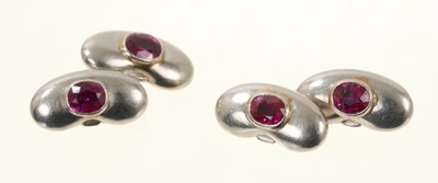 Lot 675 - Pair of platinum and ruby cufflinks in the form of lucky beans, each with an oval mixed cut ruby in rub over setting.