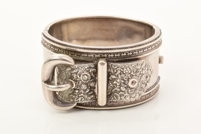 Lot 676 - Victorian silver cuff bangle with belt and buckle design and floral decoration, 39mm wide.