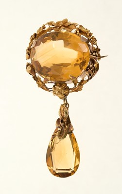 Lot 680 - Victorian citrine pendant brooch with a detachable pear cut citrine drop suspended from a large oval citrine in gold mount with flowers and foliage, 76mm.