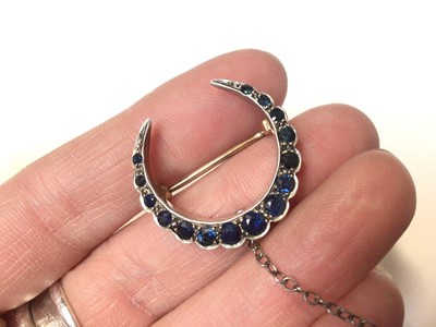 Lot 23 - Victorian sapphire crescent brooch with fifteen graduated round mixed cut blue sapphires in a yellow and white metal setting, 25mm wide