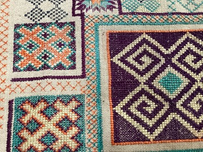 Lot 2069 - A selection of vintage textiles including an East European patchwork cover with geometric cross stitch panels connected with bobbin lace, small velvet patchwork panel, Iranian printed cotton cover...