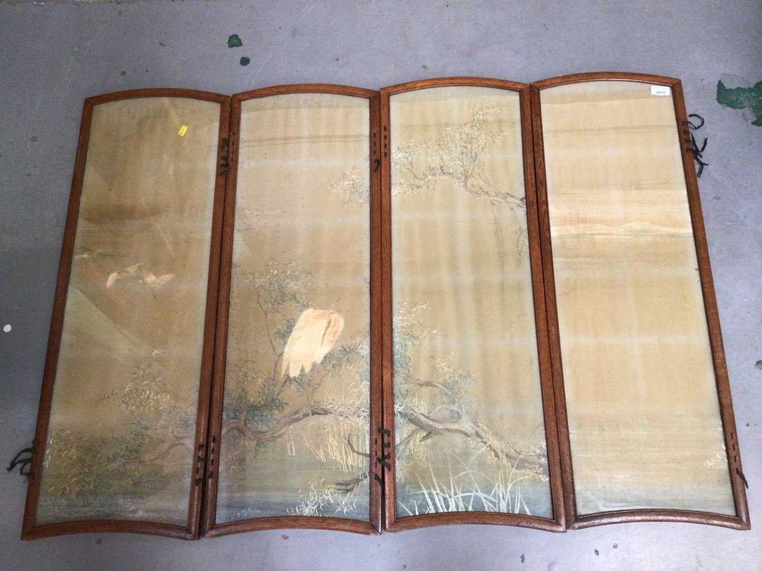 Lot 2072 - Four Japanese embroidered silk panels in oak interlacing frames making up a small folding screen, muted landscape with cranes and trees.