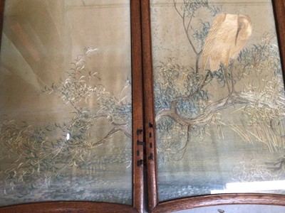 Lot 2072 - Four Japanese embroidered silk panels in oak interlacing frames making up a small folding screen, muted landscape with cranes and trees.