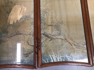 Lot 2072 - Four Japanese embroidered silk panels in oak interlacing frames making up a small folding screen, muted landscape with cranes and trees.