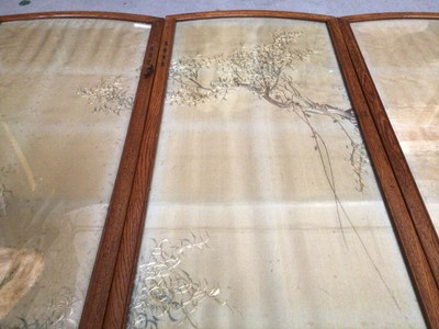 Lot 2072 - Four Japanese embroidered silk panels in oak interlacing frames making up a small folding screen, muted landscape with cranes and trees.