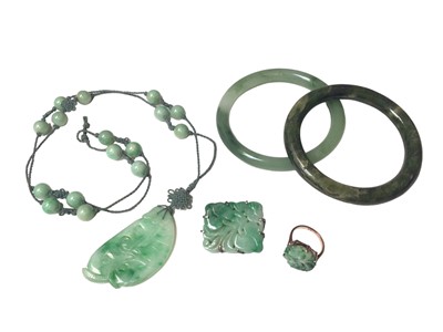 Lot 6 - Carved green hard stone/jade floral panel in 9ct gold ring mount, carved green hard stone/ jade foliate panel in a white metal brooch mount, carved green hard stone/ jade pendant necklace and two...