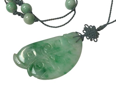 Lot 6 - Carved green hard stone/jade floral panel in 9ct gold ring mount, carved green hard stone/ jade foliate panel in a white metal brooch mount, carved green hard stone/ jade pendant necklace and two...