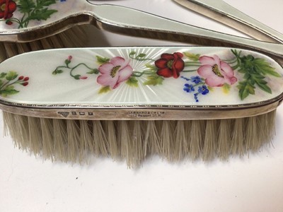 Lot 79 - Silver and enamel three piece dressing table set by Garrard & Co (Birmingham 1955) with floral decoration, together with another silver set
