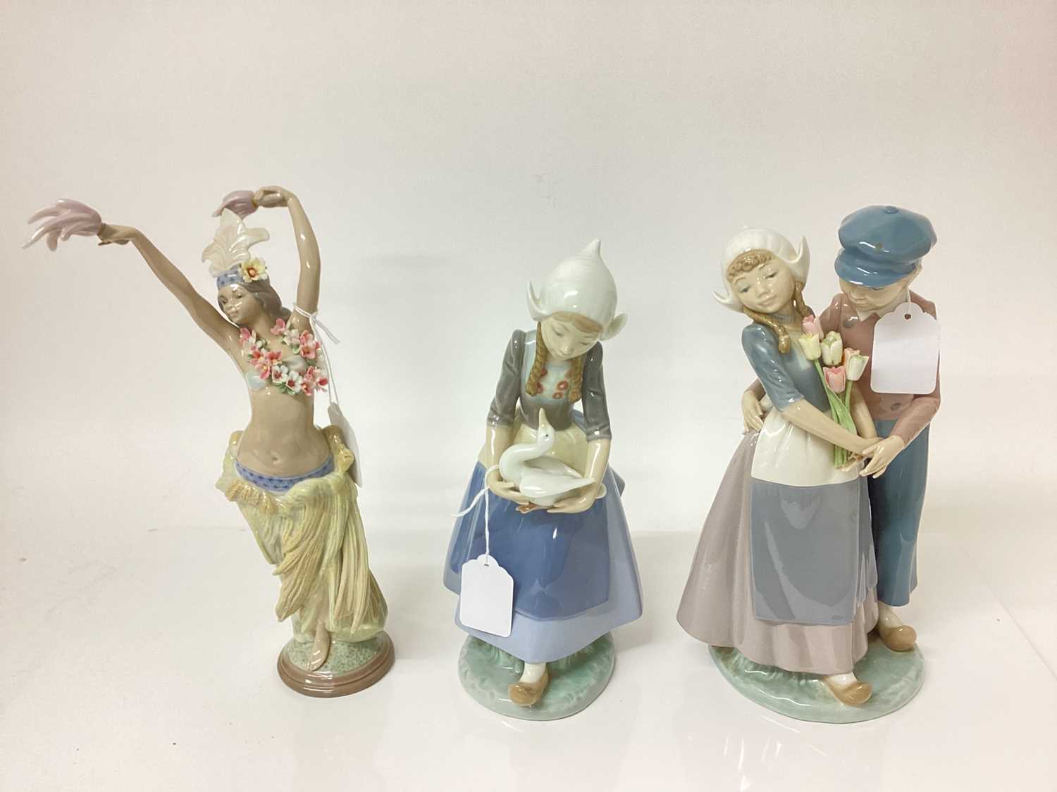 Lot 1196 - Three Lladro porcelain figures - semi clad dancer, 29cm high, Dutch couple and Dutch girl with goose