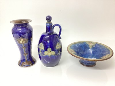 Lot 1263 - Royal Doulton stoneware vase with Art Nouveau decoration on blue ground, 22cm high, together with a decanter, 25cm high and a bowl, 21.5cm diameter (3)