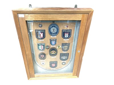Lot 211 - Glazed wall mounted cabinet containing a display of German Police badges.