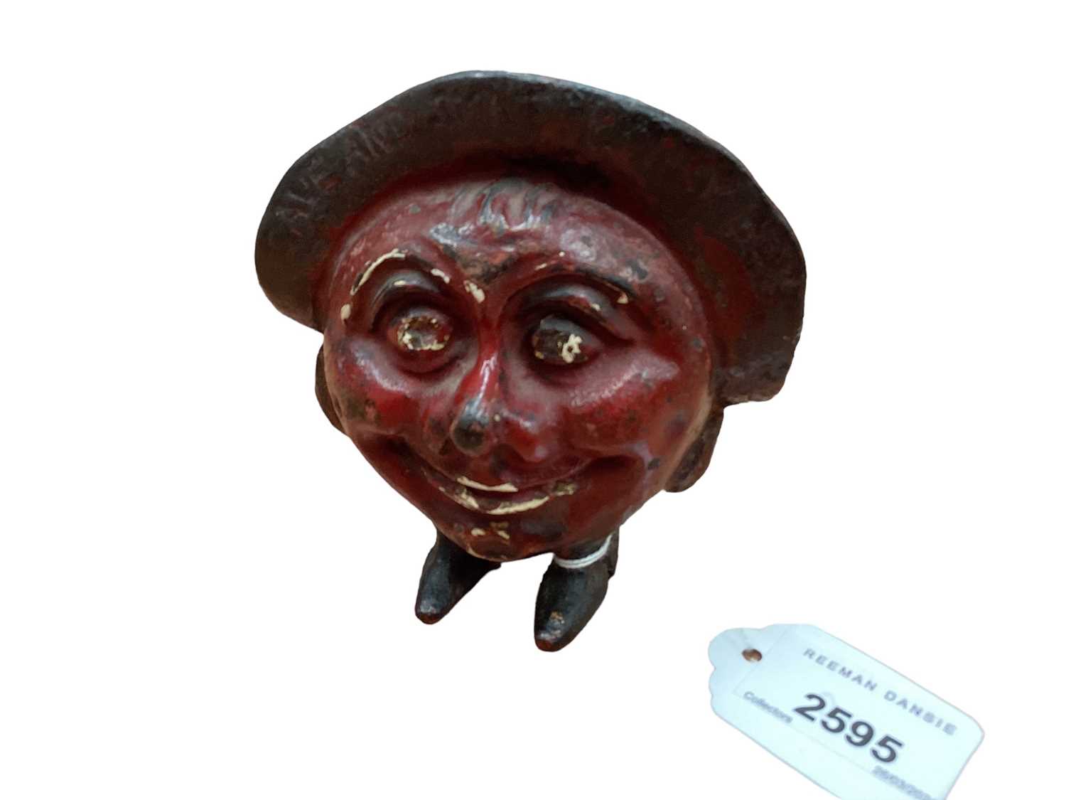 Lot 2595 - 1930s cast iron “Save and Smile” money box in the form of a smiling head mounted on two little feet, marked Made in England. 10.5cm overall height.
