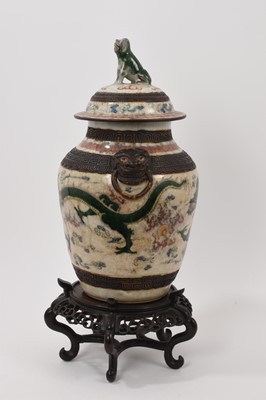 Lot 57 - Chinese famille verte crackle glazed vase and cover, circa 1900, decorated with dragons chasing a flaming pearl, mask handles and foo dog knop, four-character mark to base, with carved wooden stand...