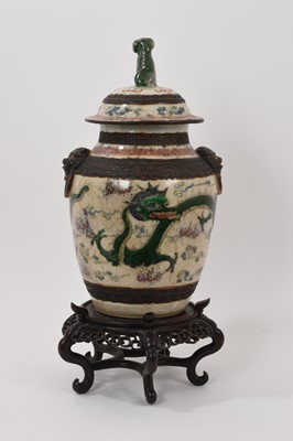 Lot 57 - Chinese famille verte crackle glazed vase and cover, circa 1900, decorated with dragons chasing a flaming pearl, mask handles and foo dog knop, four-character mark to base, with carved wooden stand...