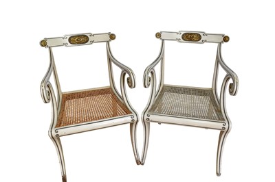 Lot 1365 - Pair of Regency style white painted and parcel gilt open elbow chairs with cane seats on sabre legs