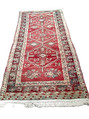 Lot 1370 - Eastern rug with three central medallions on red, blue, green and brown ground, 256cm x 118cm