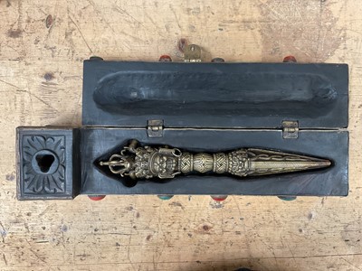 Lot 22 - Tibetan ritual dagger/Phurba in fitted carved wooden case/stand with applied decoration, the case 48cm wide