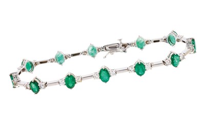 Lot 535 - Emerald and diamond bracelet with a line of twelve oval mixed cut emeralds, each flanked by two brilliant cut diamonds in white gold setting, estimated total diamond weight approximately 1ct, lengt...