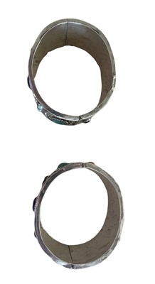 Lot 585 - Pair of Chinese silver and gem set cuff bangles, each with a lapis lazuli, turquoise and coral cabochons on floral repoussé silver ground.