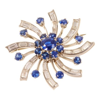 Lot 537 - 1950s diamond and sapphire ‘Catherine wheel’ brooch, the stylized spray with round mixed cut blue sapphires and tapered baguette cut diamonds in white gold setting