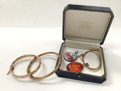 Lot 1085 - Two gold hinged bangles, silver and enamel locket and an amber pendant on plated chain