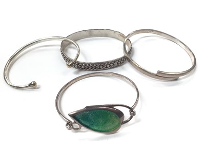 Lot 1012 - Silver bangle with green enamelled leaf decoration together with other three silver/white metal bangles (4)