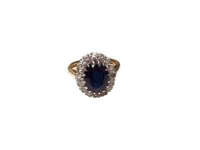 Lot 141 - 18ct gold sapphire and diamond ring with a central oval mixed cut blue sapphire surrounded by a border of diamonds