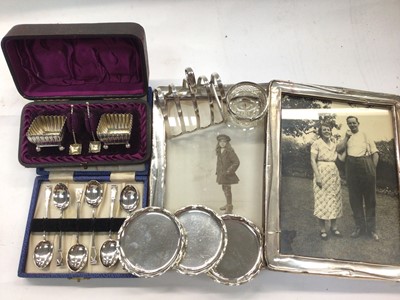 Lot 1094 - Two silver photograph frames, cased set of silver salts, set of six silver teaspoons, silver toast rack, three silver pin dishes and a silver mounted glass salt