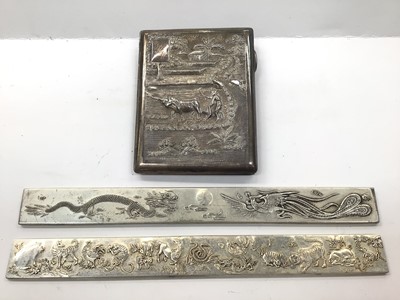 Lot 1056 - Burmese silver cigarette case with farming scene decoration, together with a pair of Chinese silver plated ingots each with dragon and animal decoration and character marks to reverse