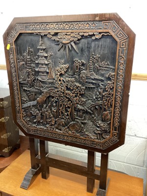 Lot 1374 - Eastern folding table with carved top depicting figures and buildings, together with an eastern octagonal chest with hinged lid and a standard lamp (3)