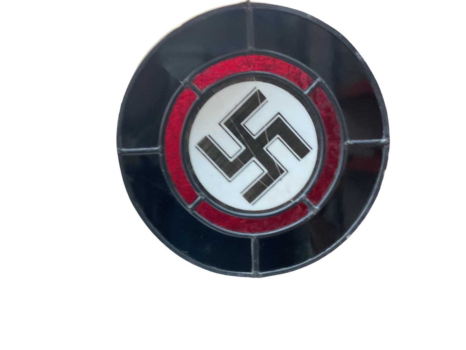 Lot 763 - Second World War Nazi Swastika stained glass panel, measuring 26cm in diameter, presented in a glazed cabinet.