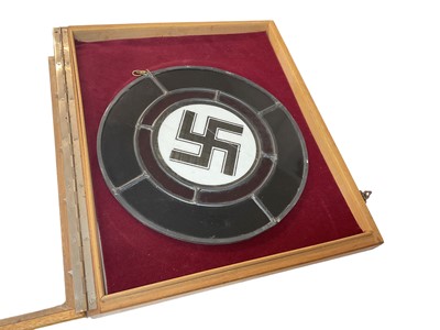 Lot 763 - Second World War Nazi Swastika stained glass panel, measuring 26cm in diameter, presented in a glazed cabinet.