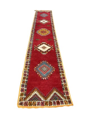 Lot 1212 - Moroccan wool runner, with five medallions on claret ground, 84 x 500cm