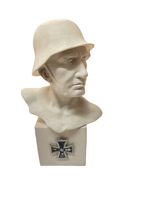 Lot 766 - Reconstituted stone bust of a German soldier, raised on a square base with applied replica Nazi Iron Cross, 17.5cm in height.