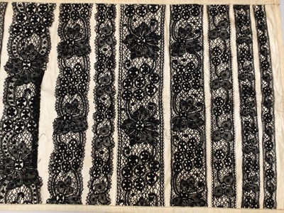 Lot 2114 - Lace items including sampler of black bobbin lace in varying width mounted on silk, deep flounce of decorated net lace with scallop edge