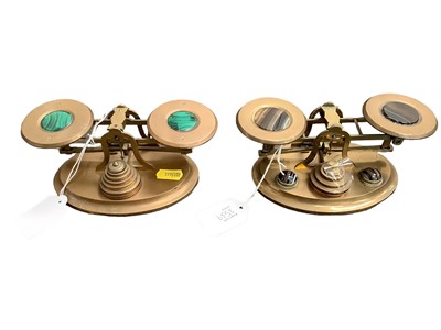 Lot 2539 - Two pairs of Victorian brass postal scales inset with malachite and tigers eye on oval bases 14cm wide, complete with graduated brass weights