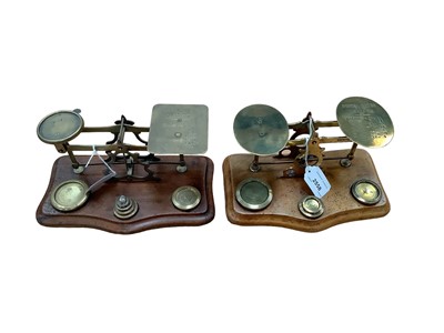 Lot 2558 - Two pairs Victorian brass postal scales with weights on shaped walnut bases (2)