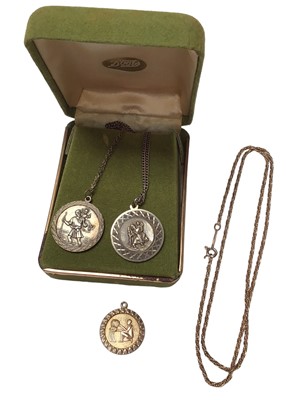 Lot 333 - 9ct gold pendant decorated with a figure emptying a basket, on a 9ct chain, together with two silver St Christopher medals on chains (3)