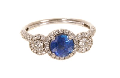 Lot 550 - Sapphire and diamond triple cluster ring a central round mixed-cut blue sapphire flanked by two brilliant cut diamonds surrounded by further brilliant cut diamonds and pavé set shoulders. Ring size...