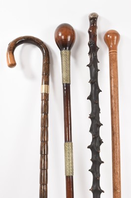 Lot 841 - Interesting group of walking sticks including a Pitcairn Islands stick, silver mounted briar stick with military crest, metal bound tribal stick or knobkerry, 9ct gold mounted stick by Swaine-Brigg...