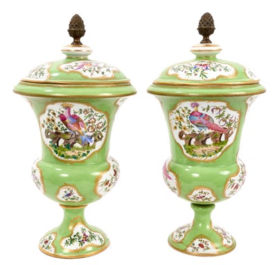 Lot 306 - Pair of continental porcelain covered vases, circa 1900, polychrome painted with panels of exotic birds on a green and gilt ground, brass acorn finials, 34cm high