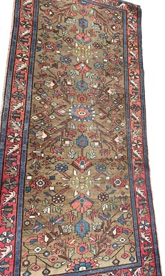 Lot 1305 - Persian rug, with angular floral ornament on biscuit ground, in foliage border, 240 x 120cm